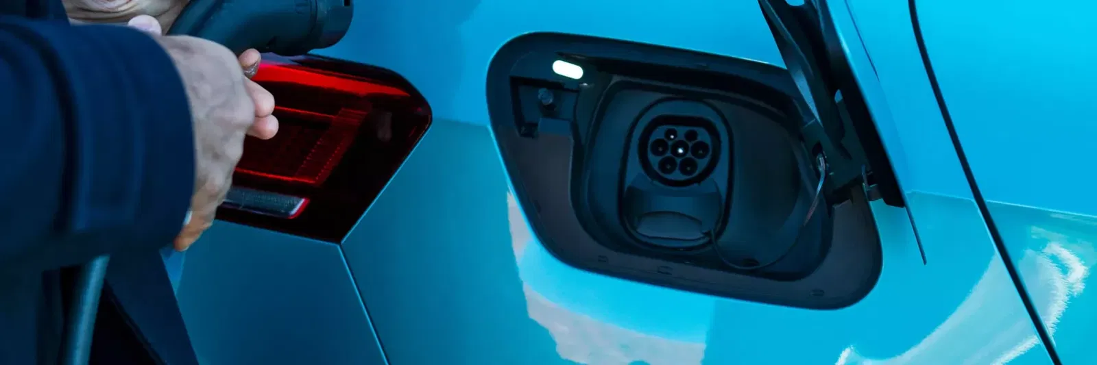 close up of an open charging port with someone about to plug a charging cable in
