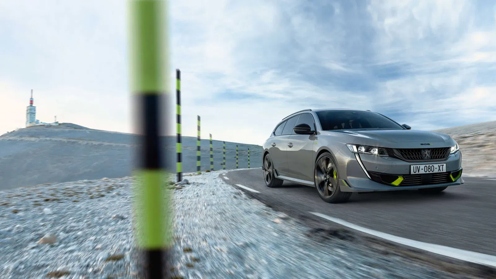 grey Peugeot 508 sw pse with lime exterior detailing driving round a corner with posts