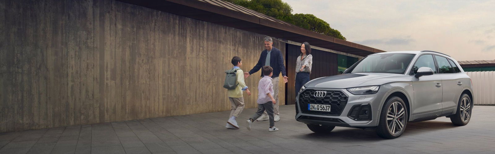 Kids running to mum and dad next to an approved used Audi