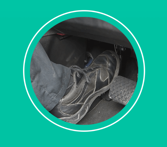 close up of someone in trainers pushing down the pedal of a car