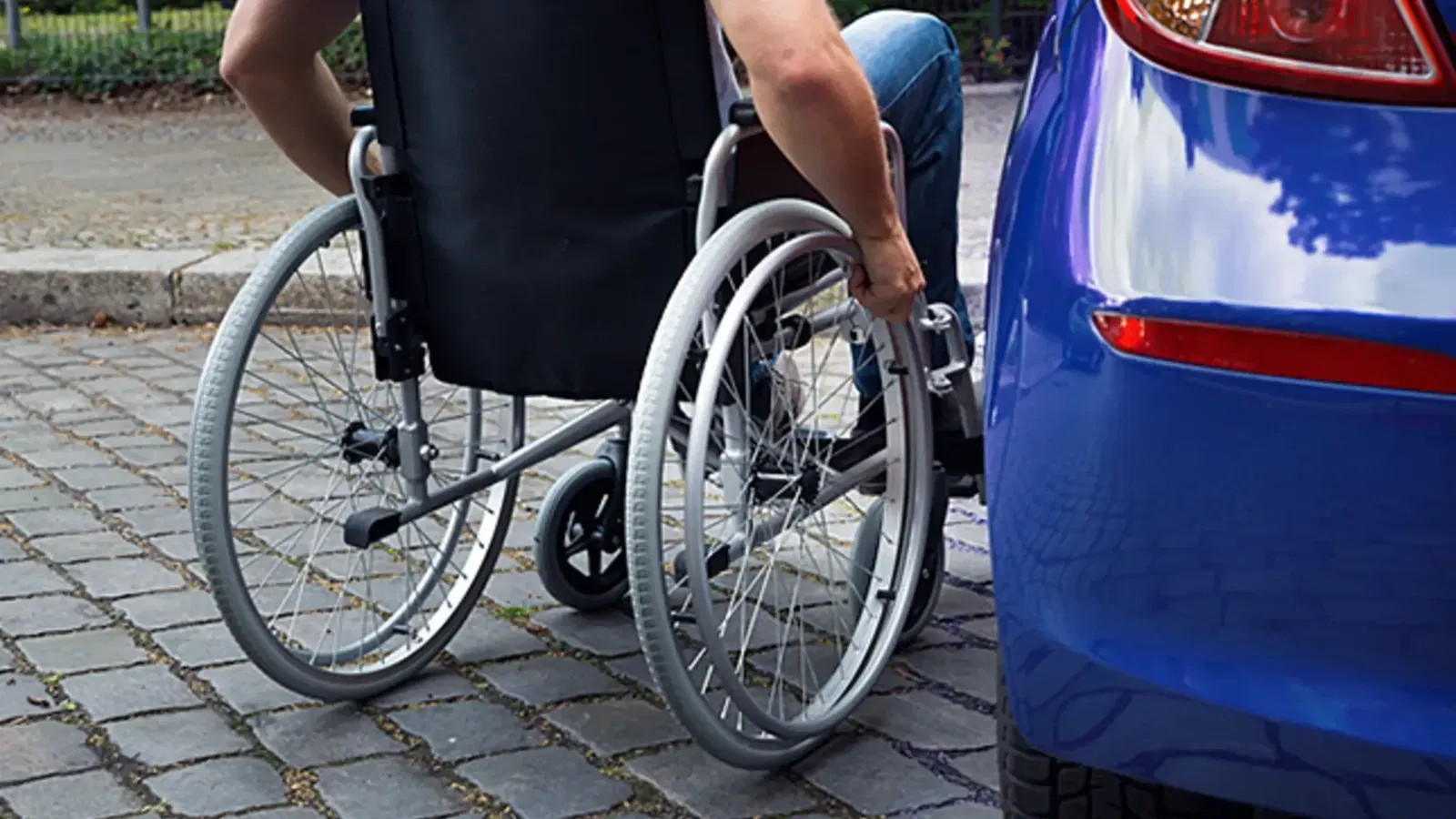Man in wheelchair next to car