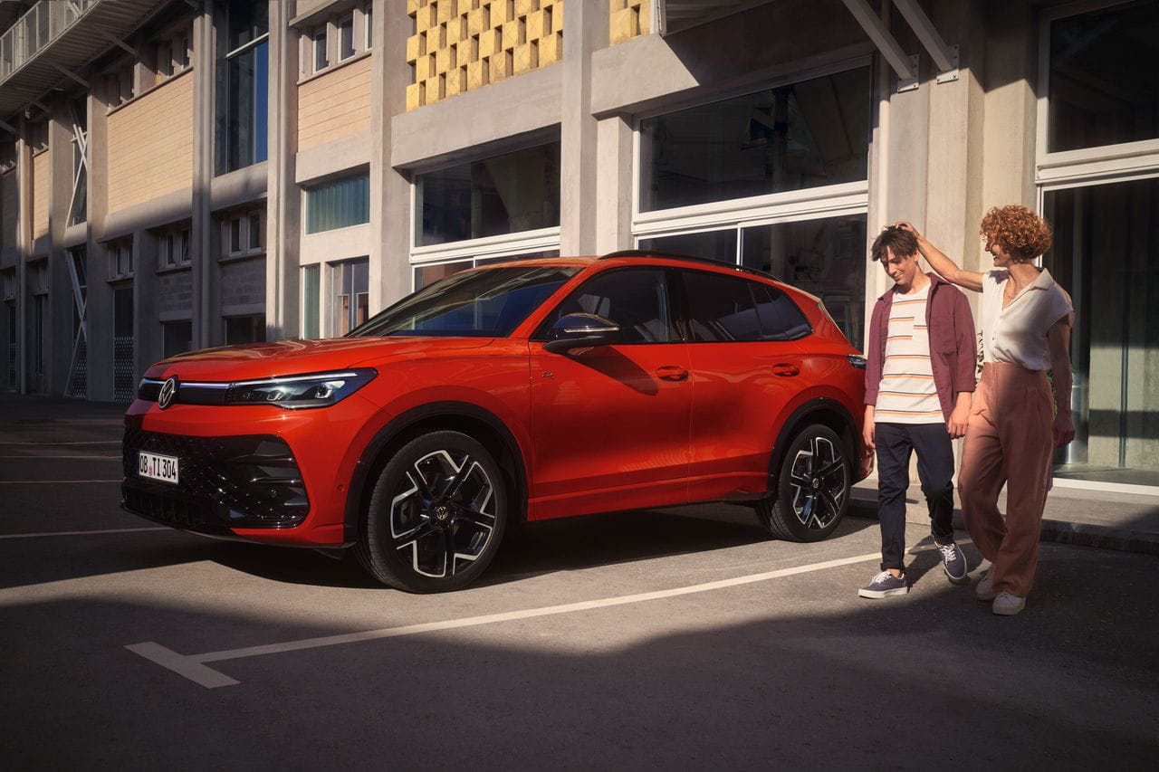 Two people stood beside red Volkswagen Tiguan