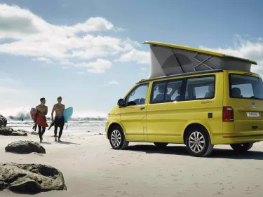 Side view of yellow Volkswagen California camper parked on a beach